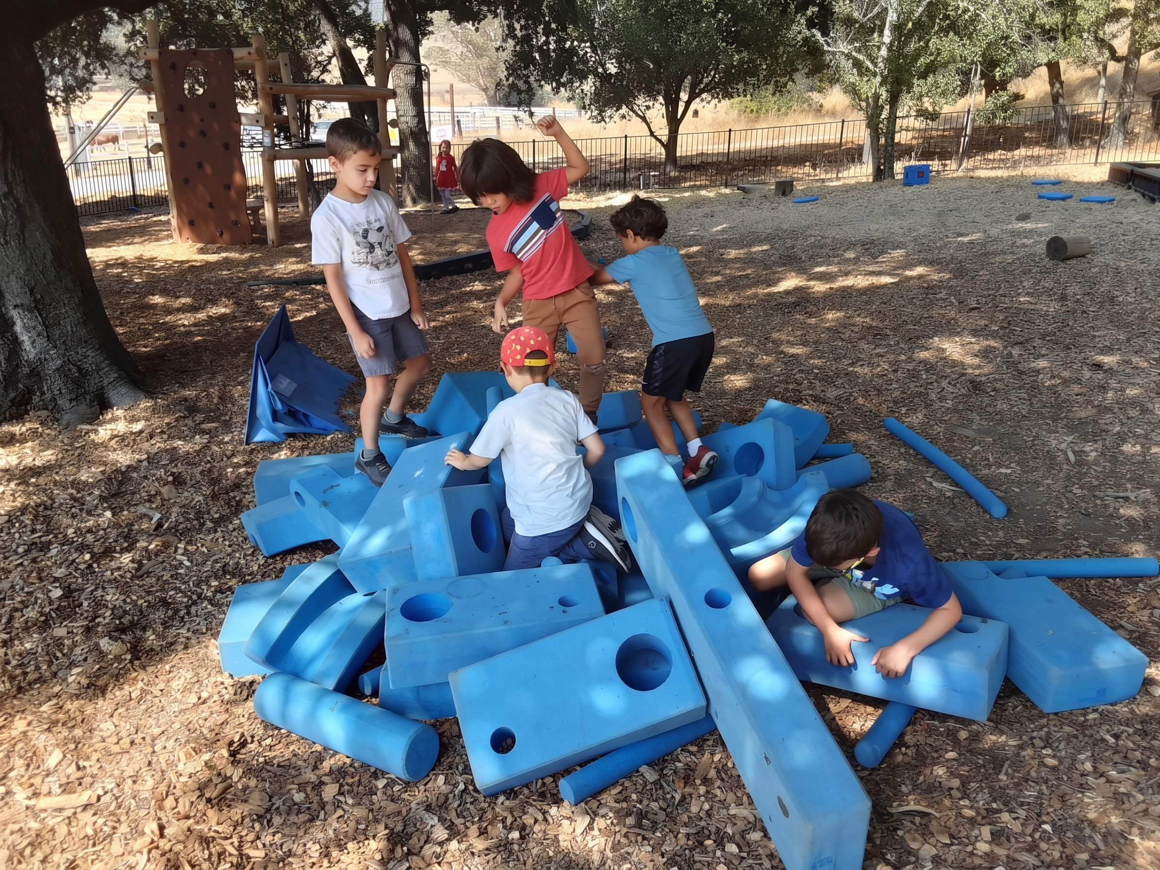 Students building a fort from giant blue foam blocks after school