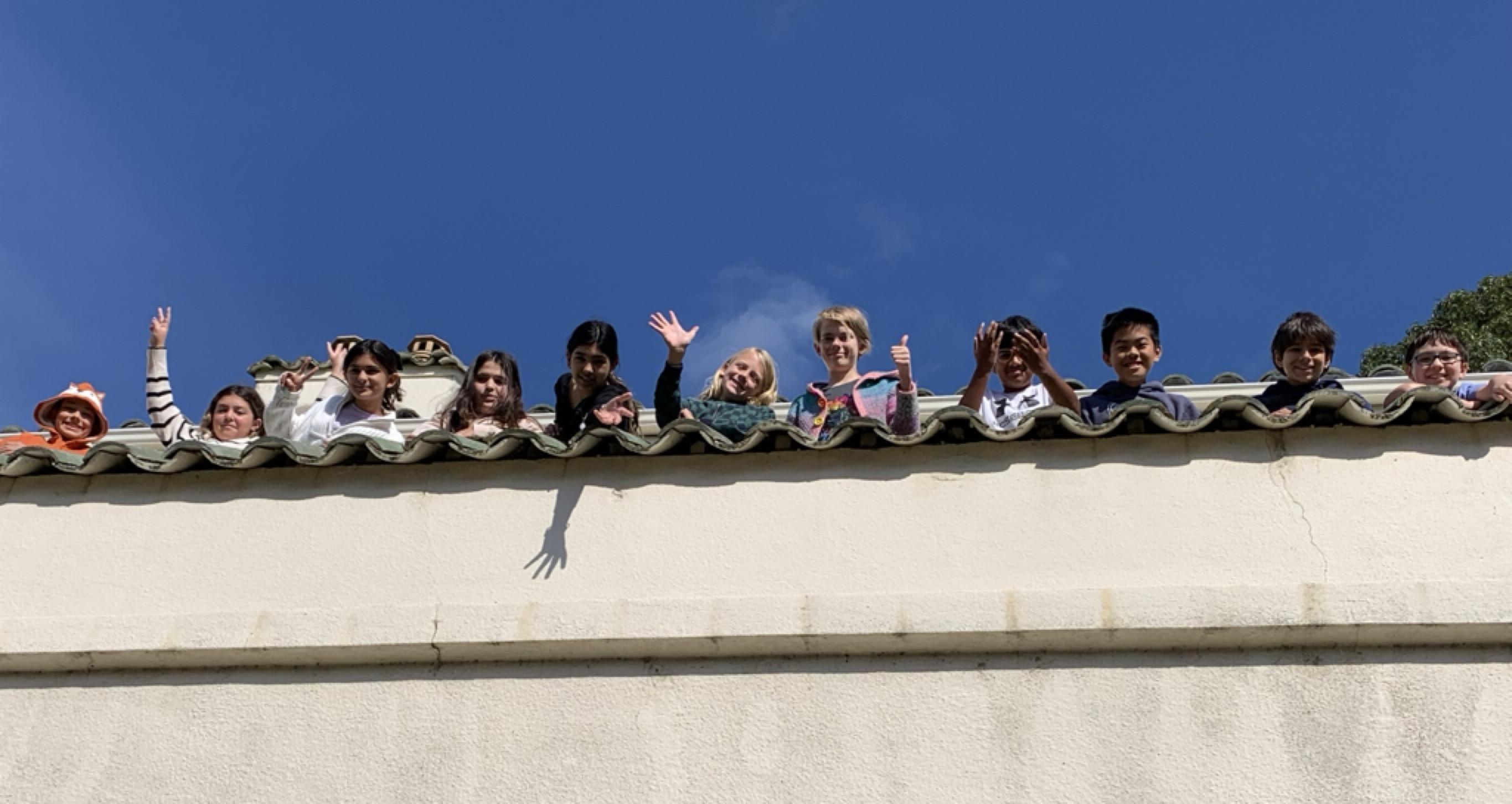 GATE students waving from a rooftop walkway