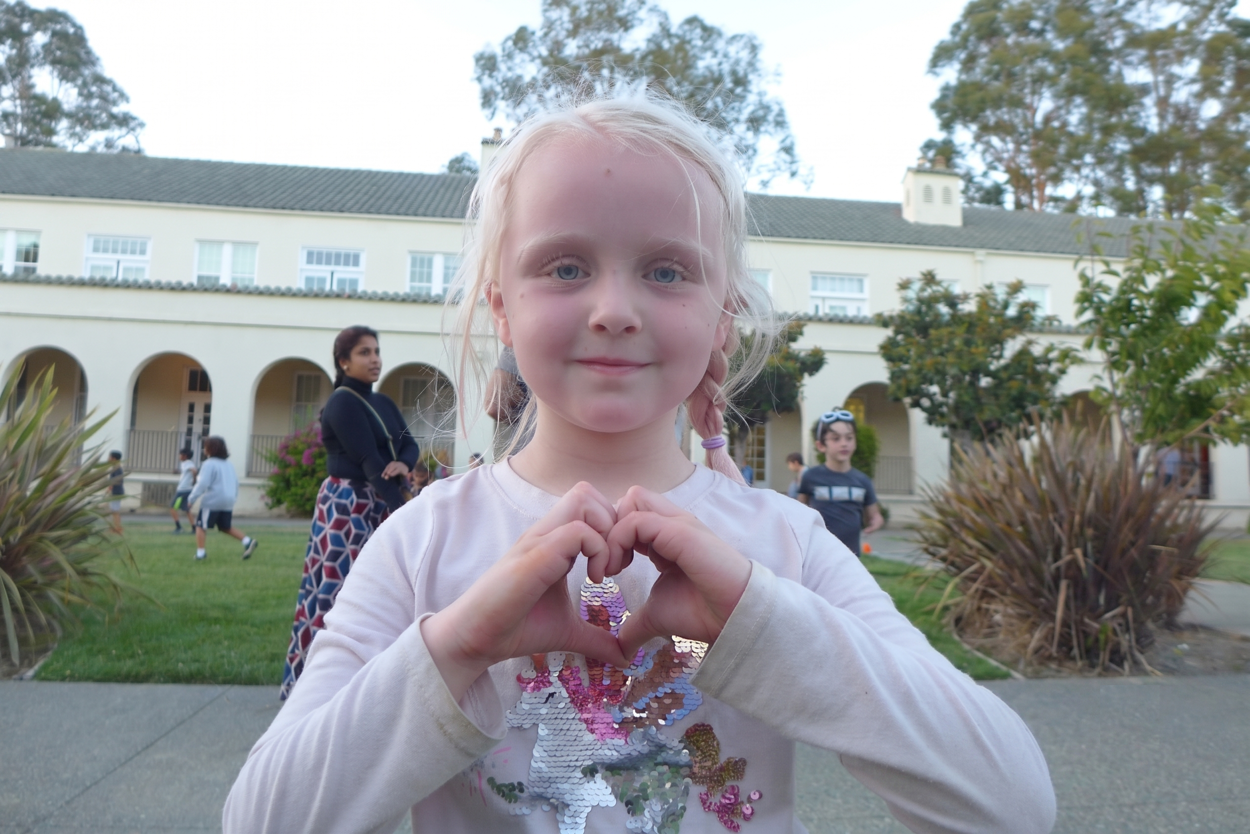 A GATE student making a heart with her hands on the school lawn